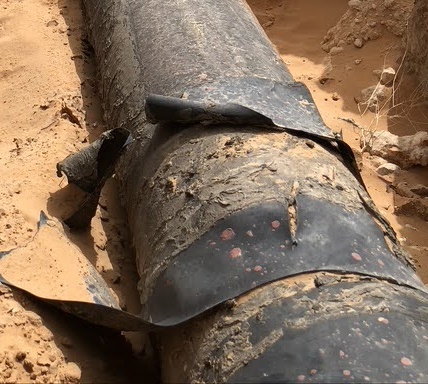 Illustrative FIMS field photograph showing peeling black pipeline coating.